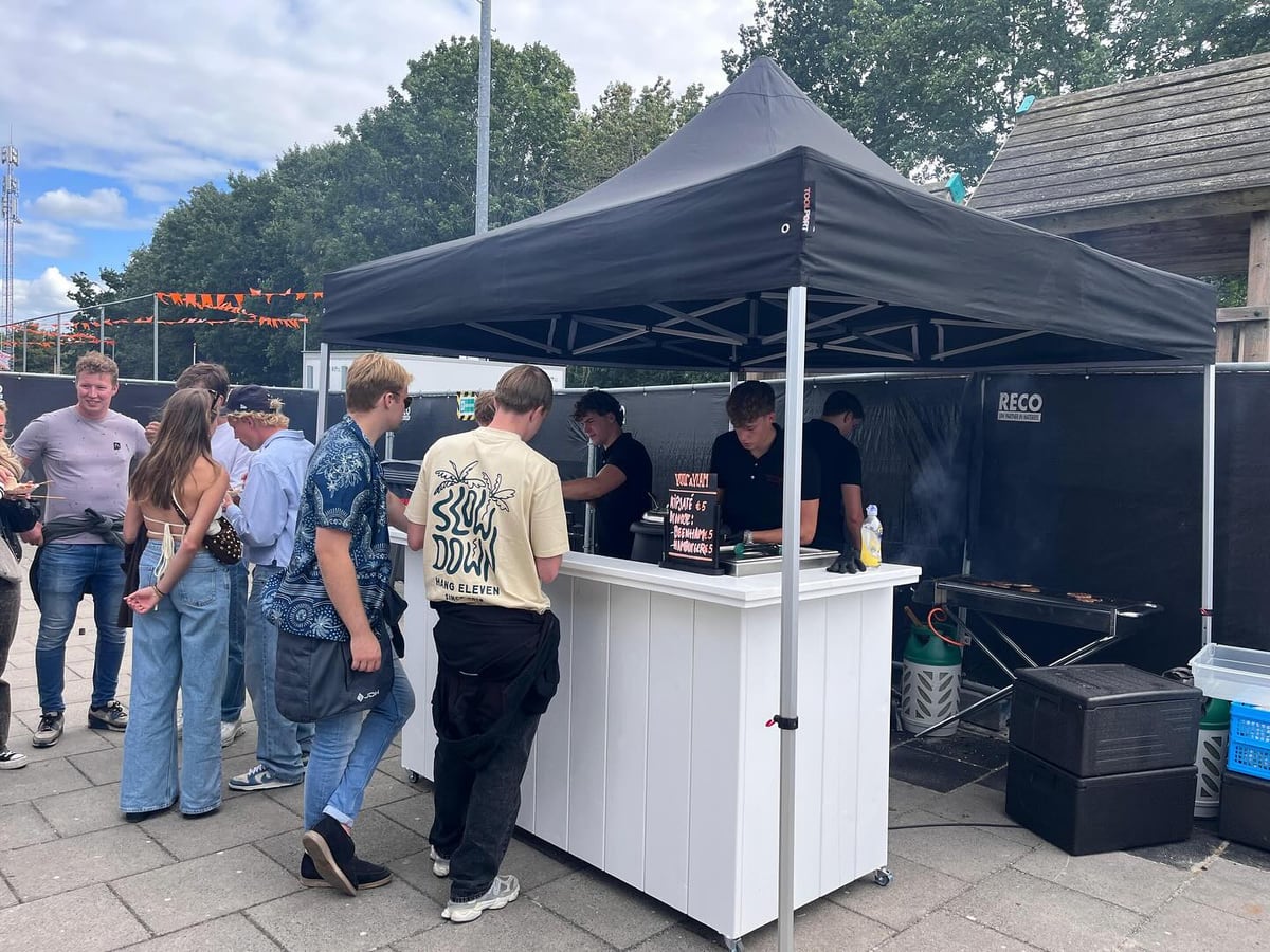 De kraam van Vuur en Vlam onder een zwarte partytent, met gasten in de rij