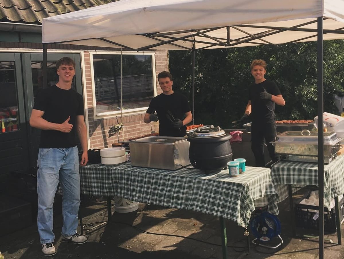 Drie medewerkers van Vuur en Vlam bij gedekte tafels onder een witte partytent