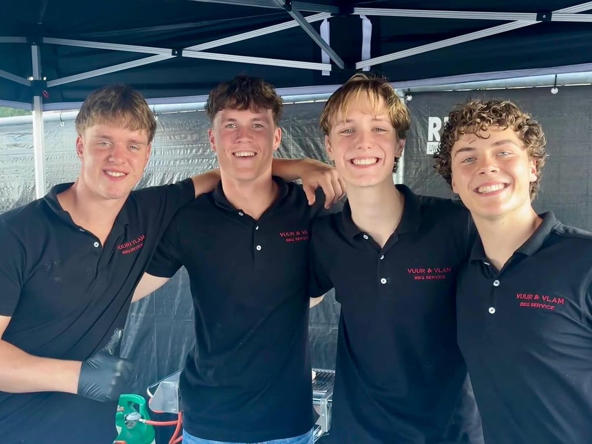 Vier medewerkers van Vuur en Vlam in zwarte shirts, arm in arm onder de partytent bij Altior in Langeraar